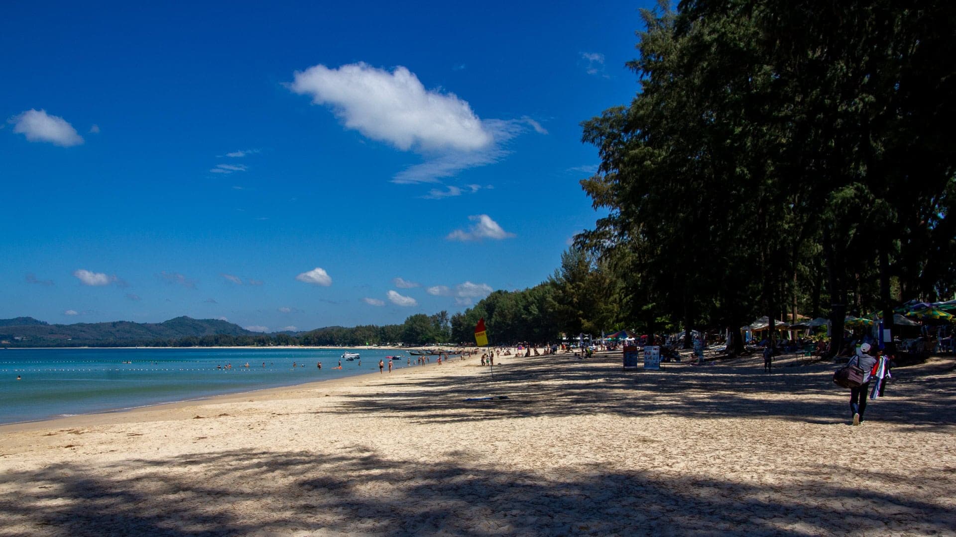 eye level along the waterline looking north: casuarina shade, swimmers, calm water