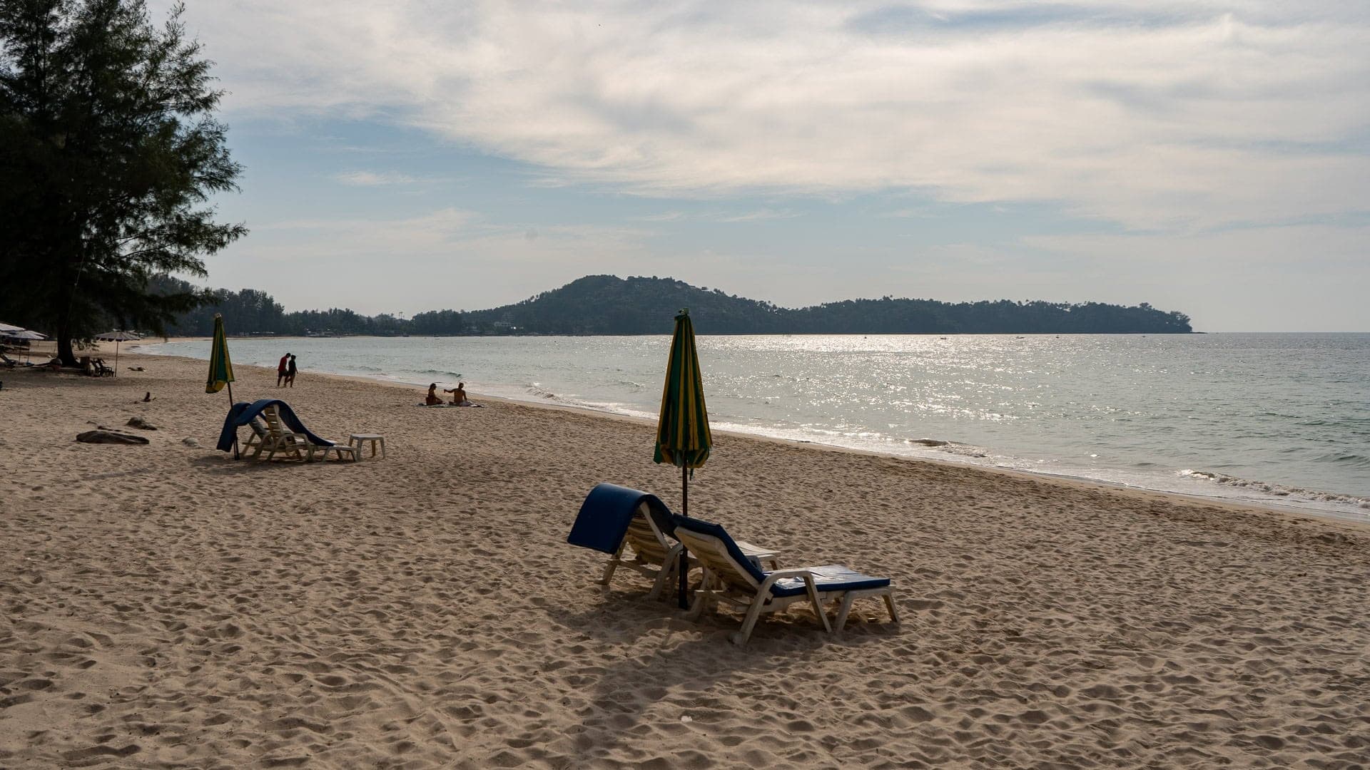 loungers and a closed umbrella on the sand in the late afternoon