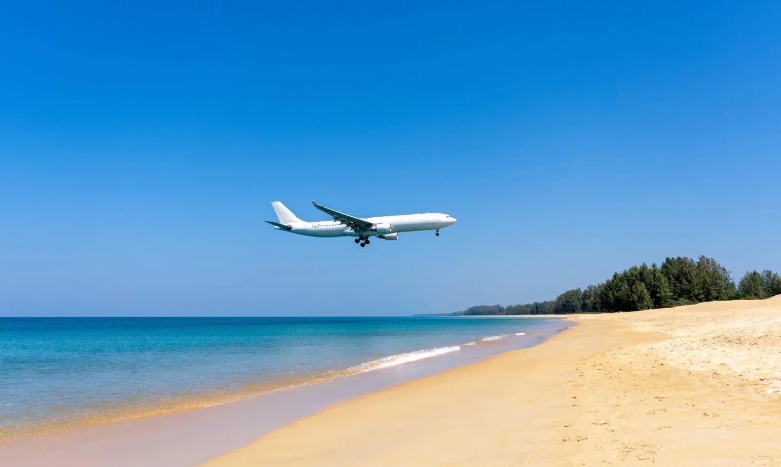 a plane landing over the beach